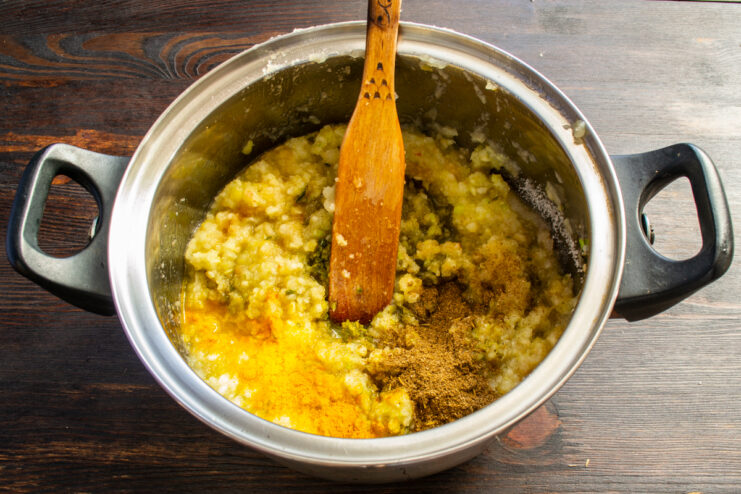 Adding the Spices Stirring khmeli-suneli and bright turmeric into the simmering apple mixture