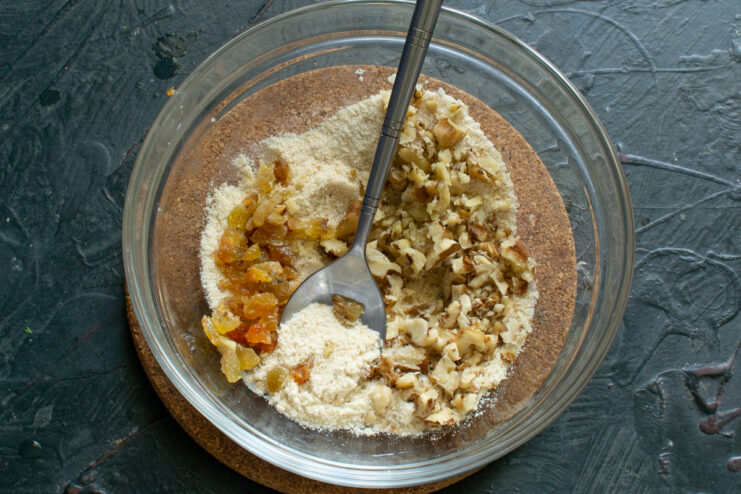 Adding walnuts and raisins to the filling Chopped walnuts and raisins added to breadcrumbs in a bowl.