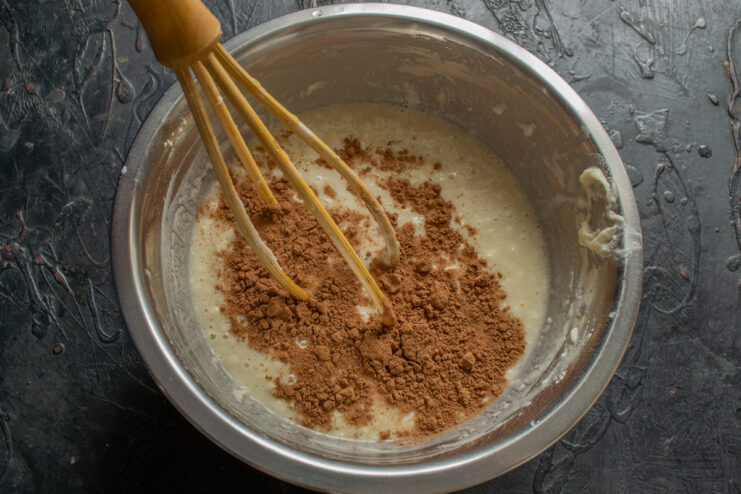 Mixing cocoa powder into the crepe batter Adding dark cocoa powder to the crepe batter mixture