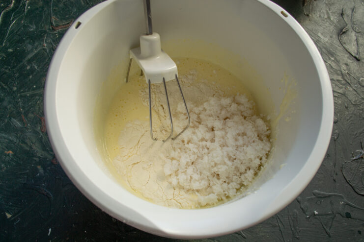 Mixing the coconut dough Adding freshly grated coconut and flour to the beaten eggs