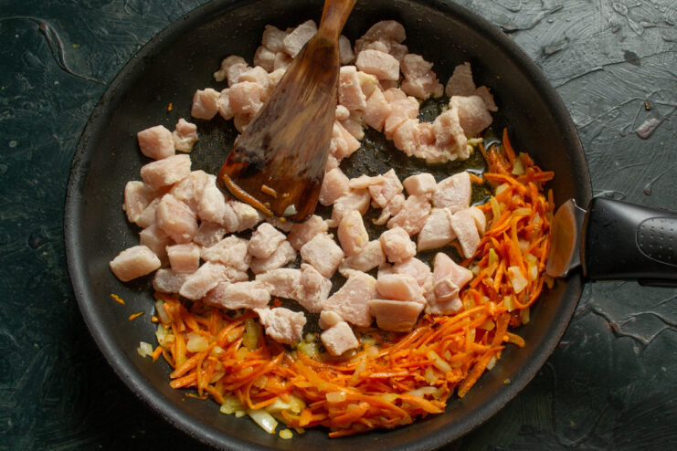 Frying the chicken pieces Adding diced chicken fillet to the pan with sauteed vegetables