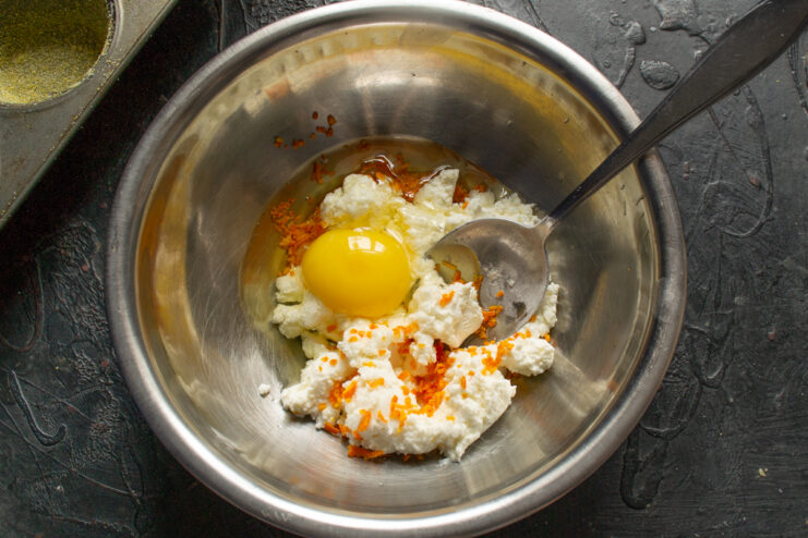 Adding the egg to the batter Cracking a chicken egg into the bowl with the cheese and zest mixture