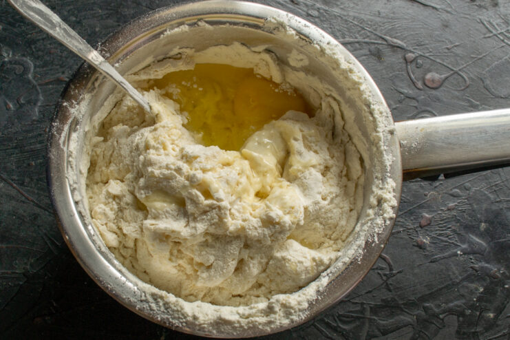 Mixing a chicken egg into the hot dough mixture