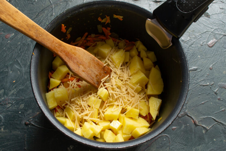 Adding vermicelli to the soup Adding fine vermicelli pasta to a pot with potatoes and sautéed vegetables.
