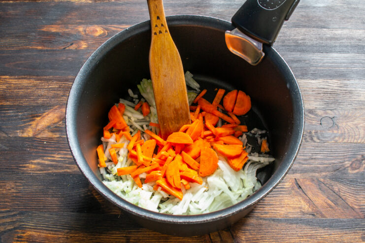 Adding the carrots Adding julienned carrots to sautéed onions in a pan