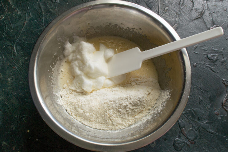 Mixing the sponge cake batter Folding sifted flour and whipped egg whites into the yolk mixture