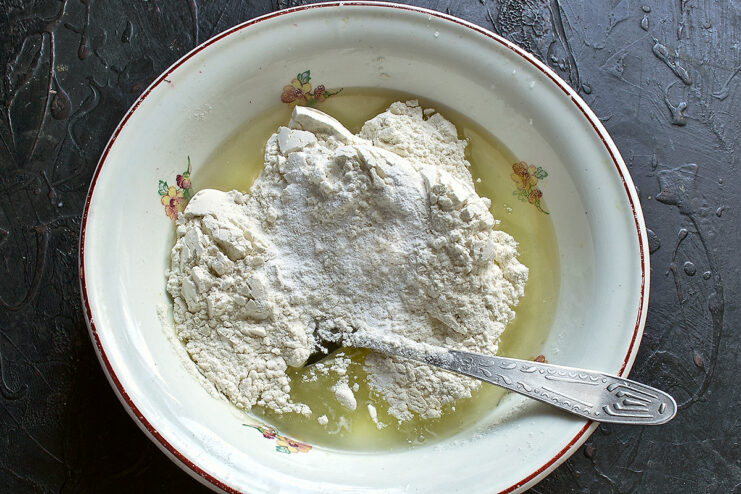 Adding dry ingredients to the bowl. Pouring flour and baking powder into the wet ingredient mixture
