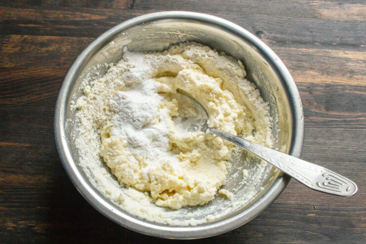Kneading the syrniki dough Folding flour and powdered sugar into the syrniki dough