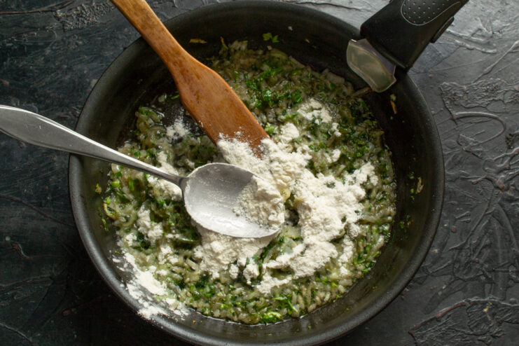 Cooking the flour base Flour mixed with sautéed onions and herbs in a pan
