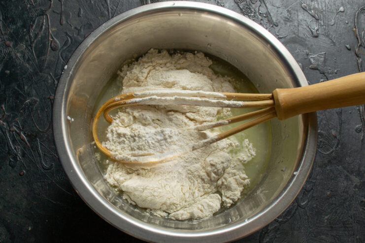 Adding dry ingredients to the liquid mixture Adding flour baking soda and baking powder to the liquid