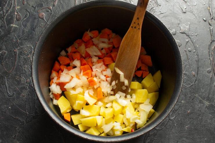 Vegetable base for the soup Adding finely chopped onions to diced carrots and potatoes