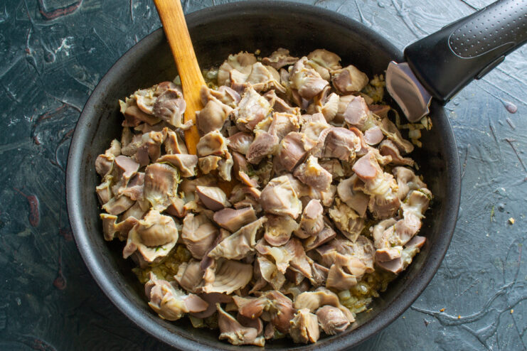 Combining the components Adding chopped gizzards to onions in a skillet
