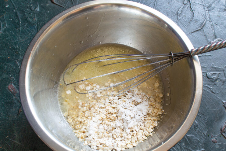 Adding dry ingredients Pouring quick-cooking oats and baking powder into the liquid batter