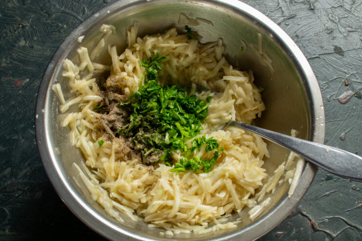 Adding spices and herbs Sprinkling fresh parsley and black pepper into the fritter batter