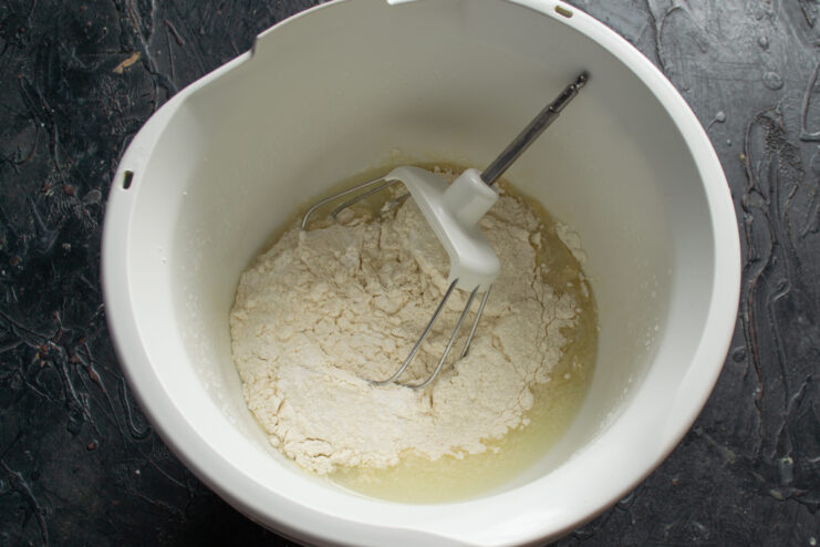 Adding dry ingredients to the liquid base Adding wheat flour and baking powder into the bowl with the liquid mixture.