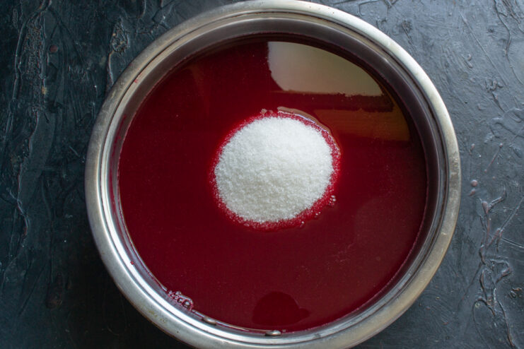Adding sugar to the syrup Adding sugar to raspberry juice in a pot