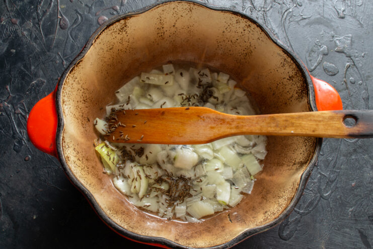 Aromatic spices for plov Adding cumin seeds to sautéed onions in a Dutch oven