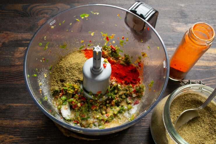 Adding spices Adding dry paprika, khmeli-suneli, and salt to the minced peppers in the bowl.