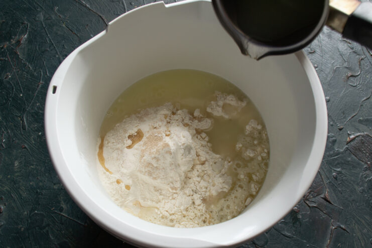 Adding water to the dough Pouring warm salted water into the flour mixture