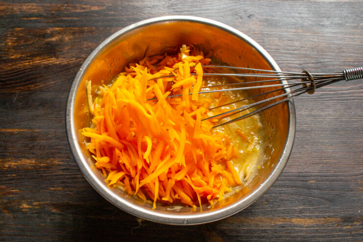 Adding grated pumpkin Mixing freshly grated pumpkin into the apple and egg batter.
