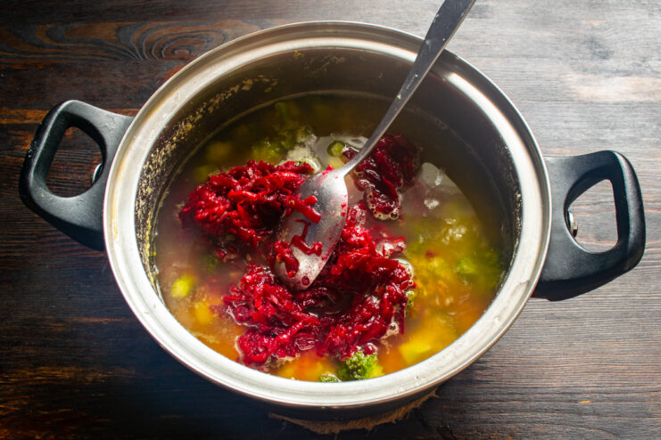 Adding the beet base Stirring the sautéed beet mixture into the soup pot