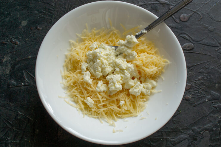 Mixing Cheese and Tvorog Adding farmers cheese to grated cheese in a bowl