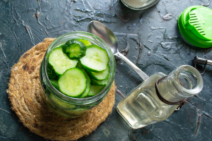 Adding Vinegar to the Jar Adding vinegar to a glass jar filled with sliced cucumbers