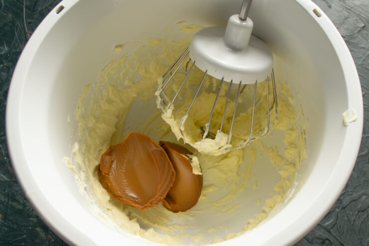 Adding boiled condensed milk to whipped butter.