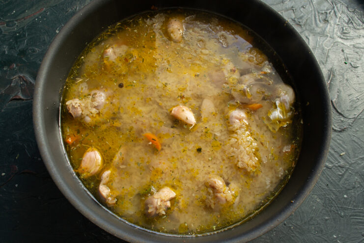 Pouring water or broth into a pot over parboiled rice and meat