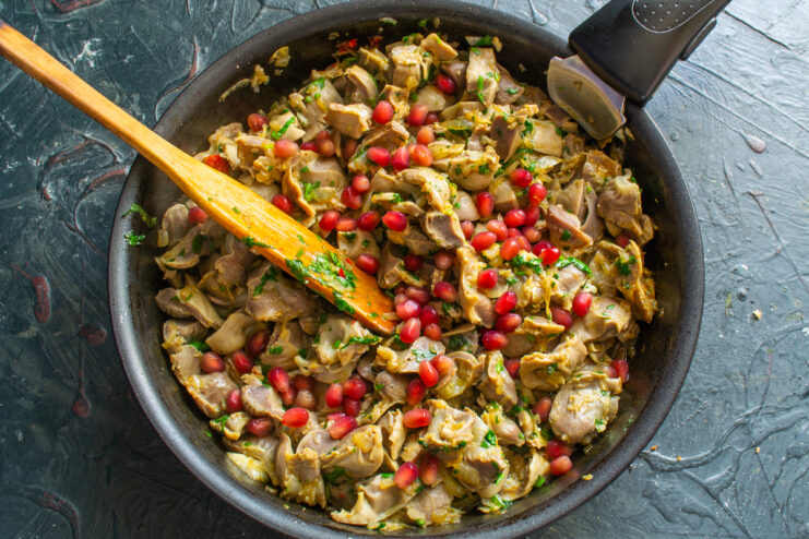 Garnishing with pomegranate Adding pomegranate seeds to a skillet with kuchmachi