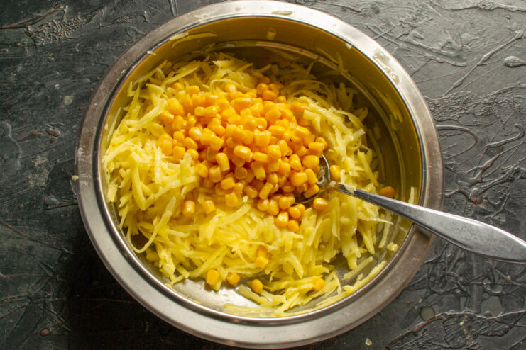 Adding sweet corn kernels Folding bright yellow corn kernels into the potato mixture