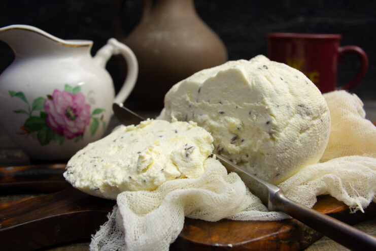 Homemade creamy caraway farmer's cheese on a rustic wooden cutting board