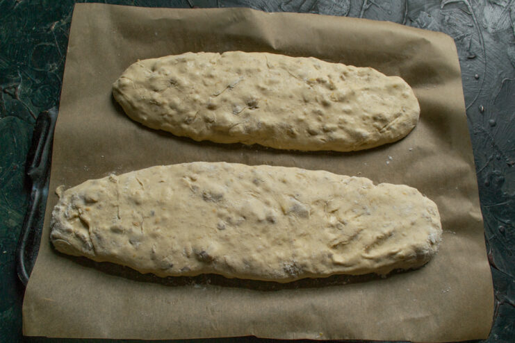 Shaping the dough logs Two raw dough logs on a parchment-lined baking sheet