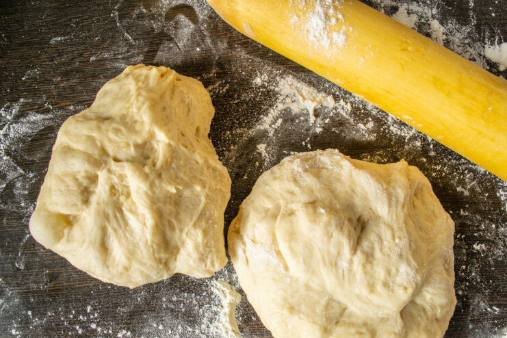 Dividing the Dough Two portions of yeast dough resting on a table next to a rolling pin