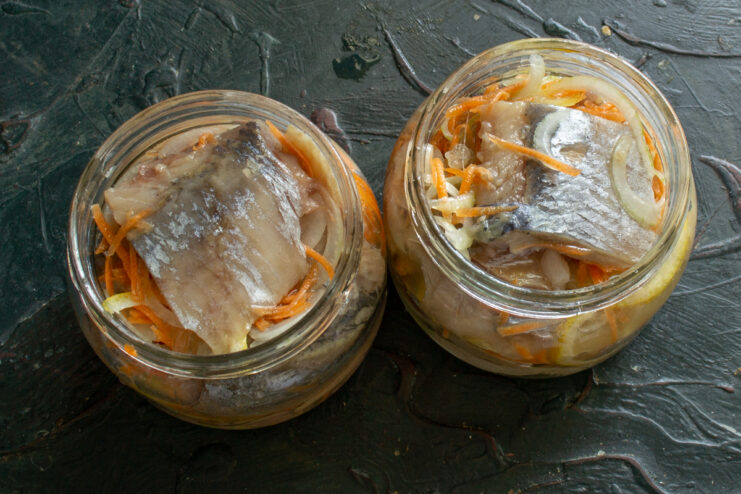 Layering ingredients in jars Alternating layers of herring, vegetables, and lemon in a jar covered with oil
