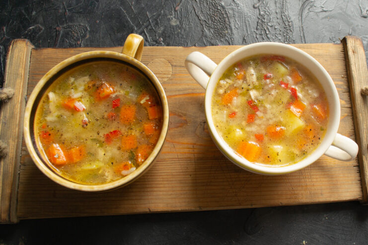 Serving the chicken soup Two bowls of chicken and rice soup served on a wooden board