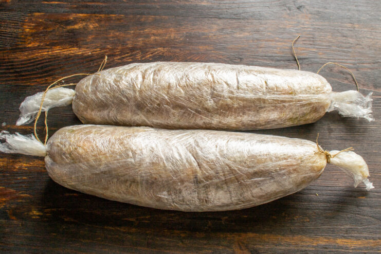 Prepared Sausage Logs Two raw chicken sausage logs tightly tied with kitchen twine