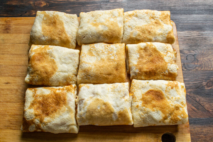 Folded crepe envelopes Stuffed crepes neatly folded into envelopes on a wooden board