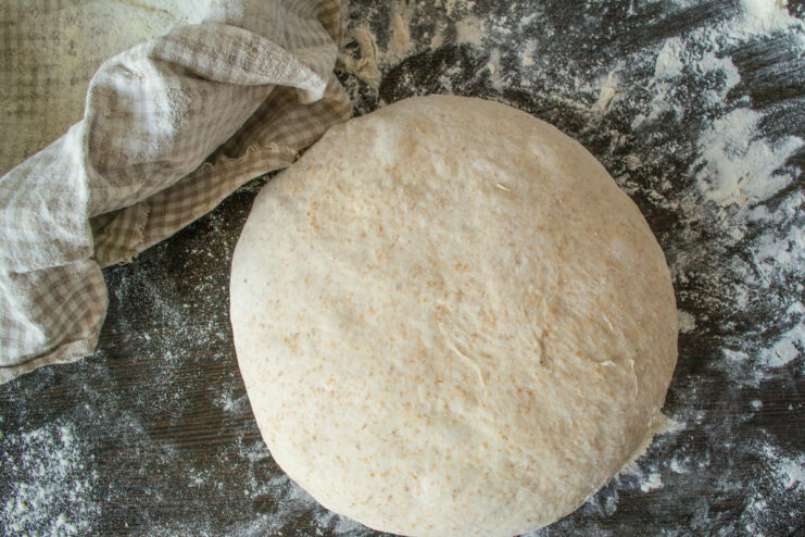Shaping The Loaf Shaping a round loaf of bread dough on a flour-dusted work surface.
