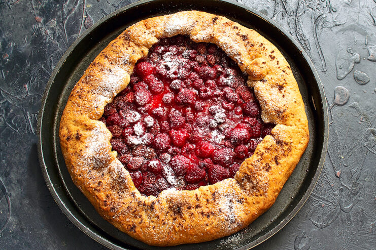Dusting the baked galette with powdered sugar. Baked berry galette being dusted with powdered sugar for serving
