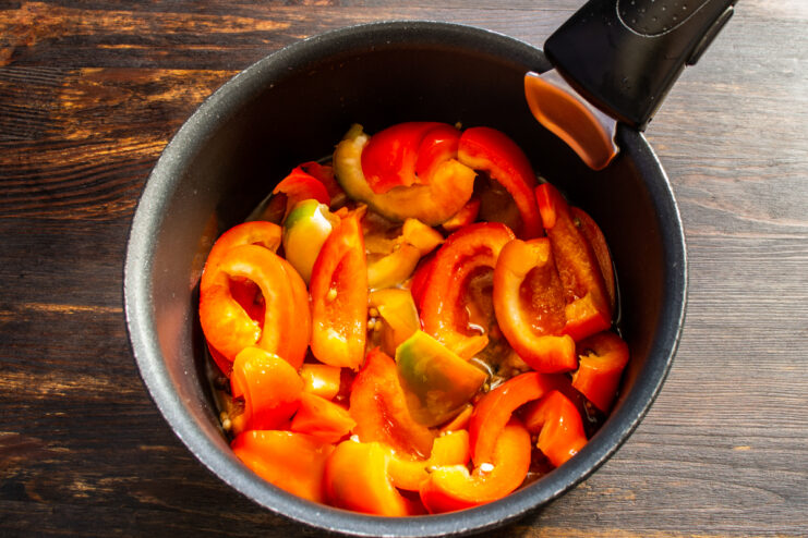 Adding peppers to the boiling marinade Sliced peppers being placed into a saucepan with boiling marinade