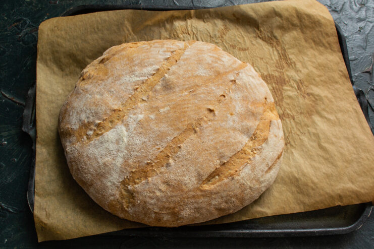 Freshly Baked Bread Hot baked whole wheat bread on a baking sheet lined with parchment paper.