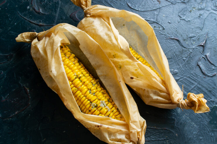Corn baked in parchment Hot baked corn resting in unwrapped parchment paper