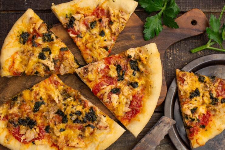 Ready thin crust pizza with chicken and cheese on a surface