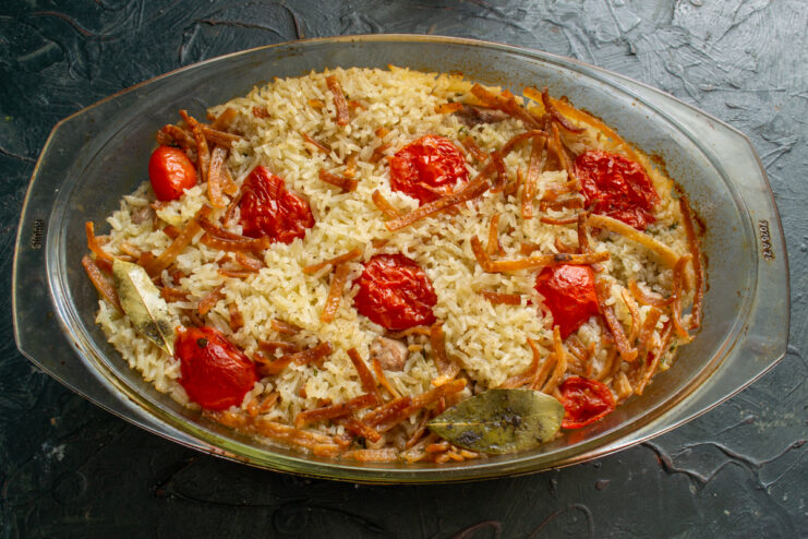 Freshly baked chicken with rice and toasted noodles inside a glass baking dish