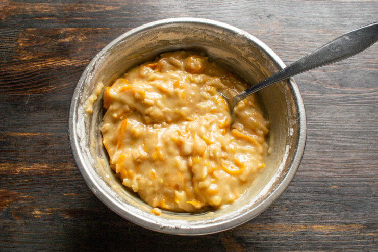 Checking the batter consistency Thick muffin batter with visible shreds of grated apple and pumpkin in a bowl.