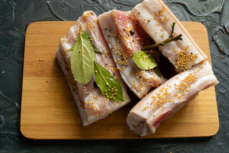 Salo with mustard after aging Finished cured salo coated in mustard seeds on a wooden board