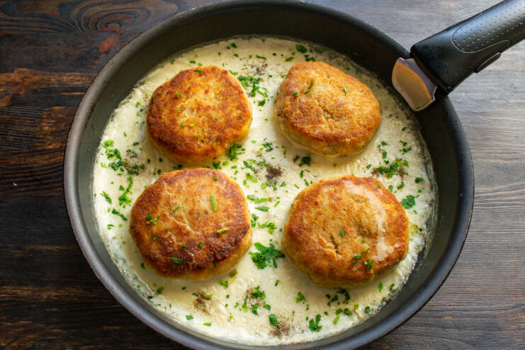 Finished dish in the skillet Finished patties in sauce sprinkled with fresh herbs