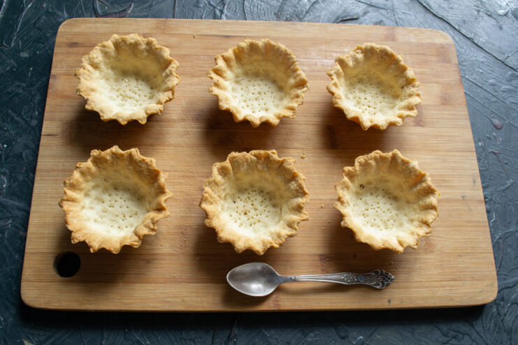 Cooling Baked Shells Baked golden tartlet shells cooling on a wooden board