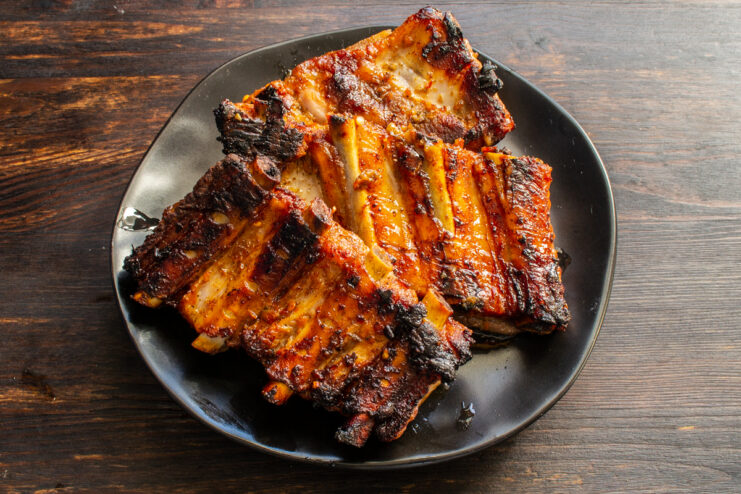 Serving the finished oven-baked ribs Finished oven-baked pork ribs with adjika served on a black plate.